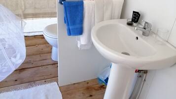 A compact bathroom with a toilet, sink, and a shower area.
