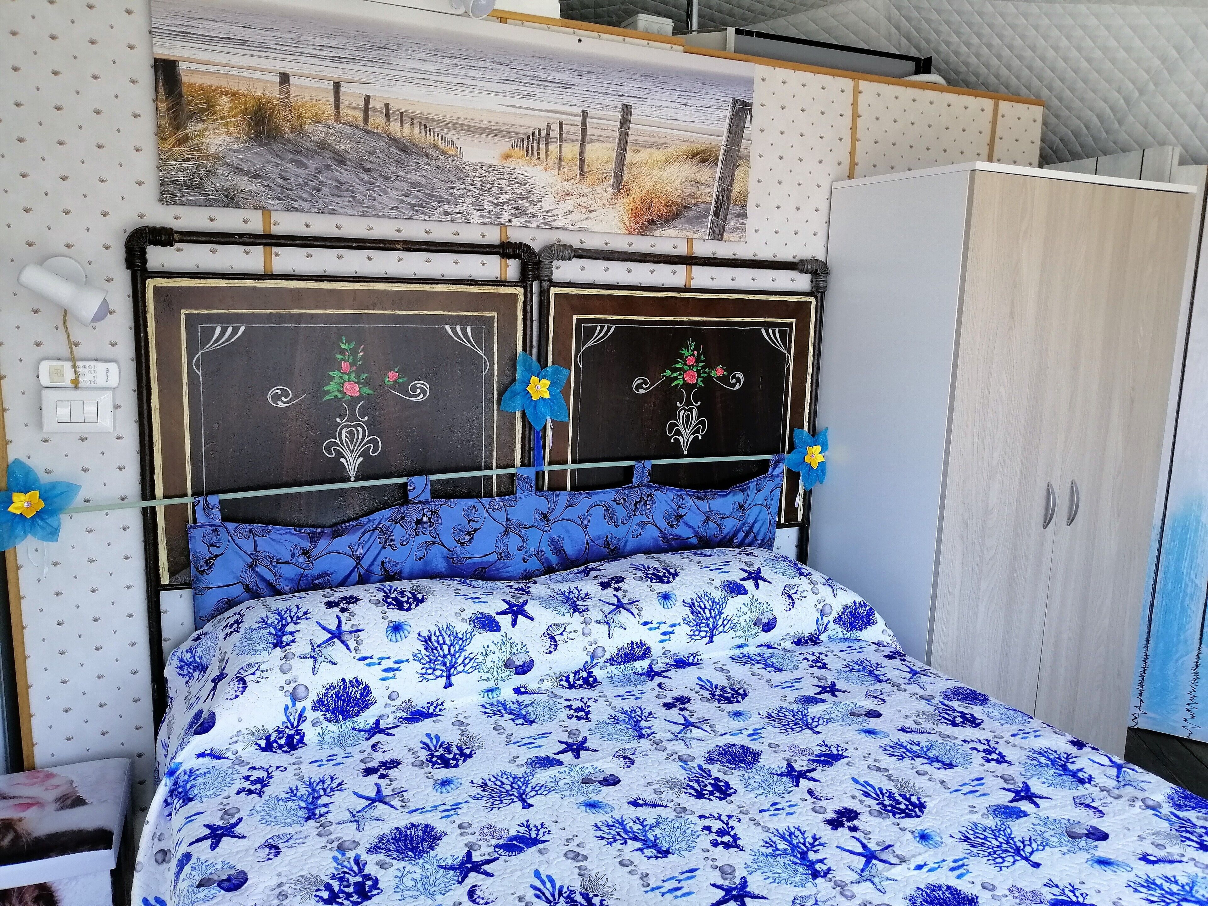 Een slaapkamer met een bed, een kledingkast en een schilderij aan de muur.