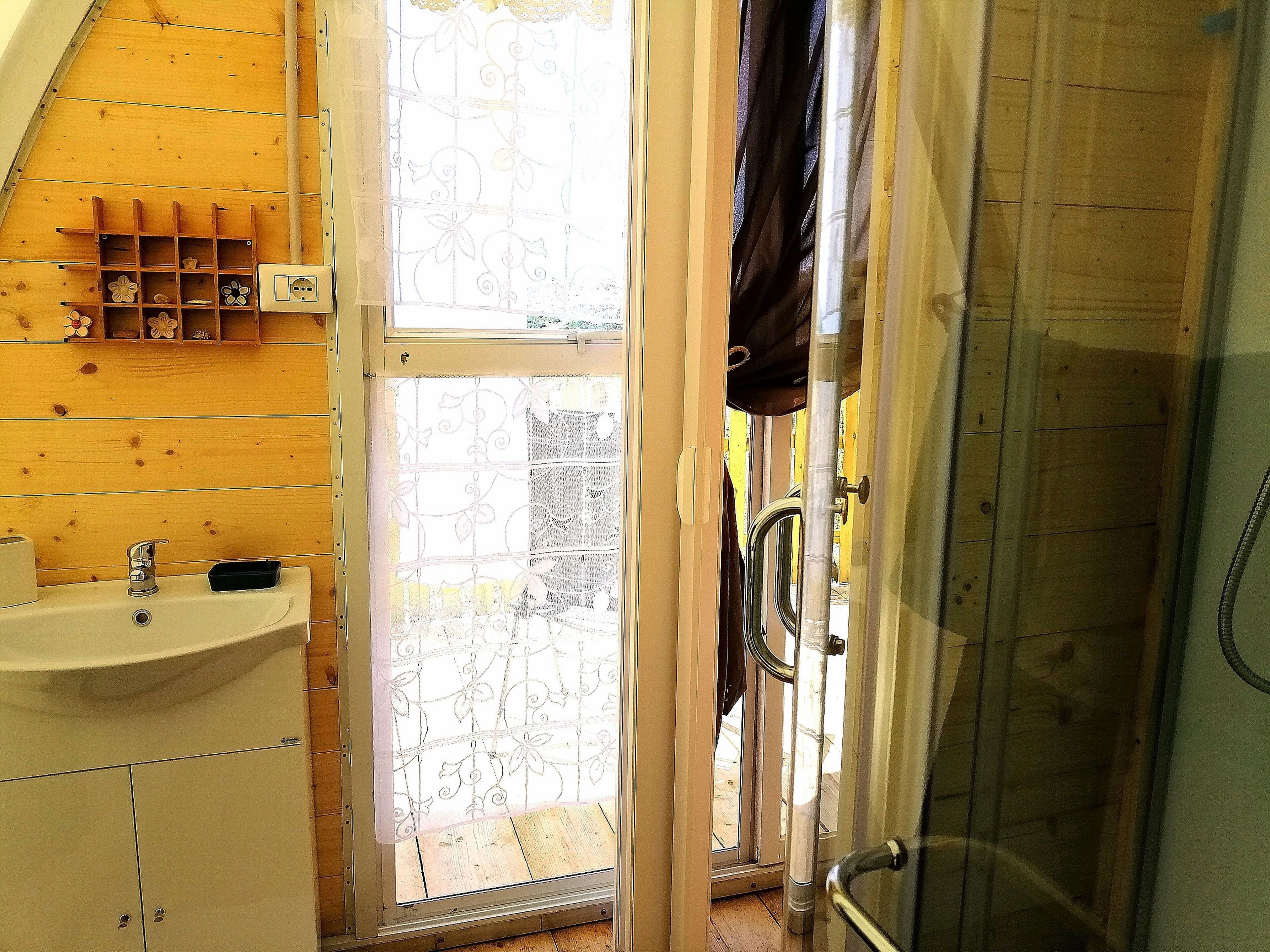 Une salle de bain équipée d’un lavabo, d’une douche et d’une fenêtre donnant sur l’extérieur.