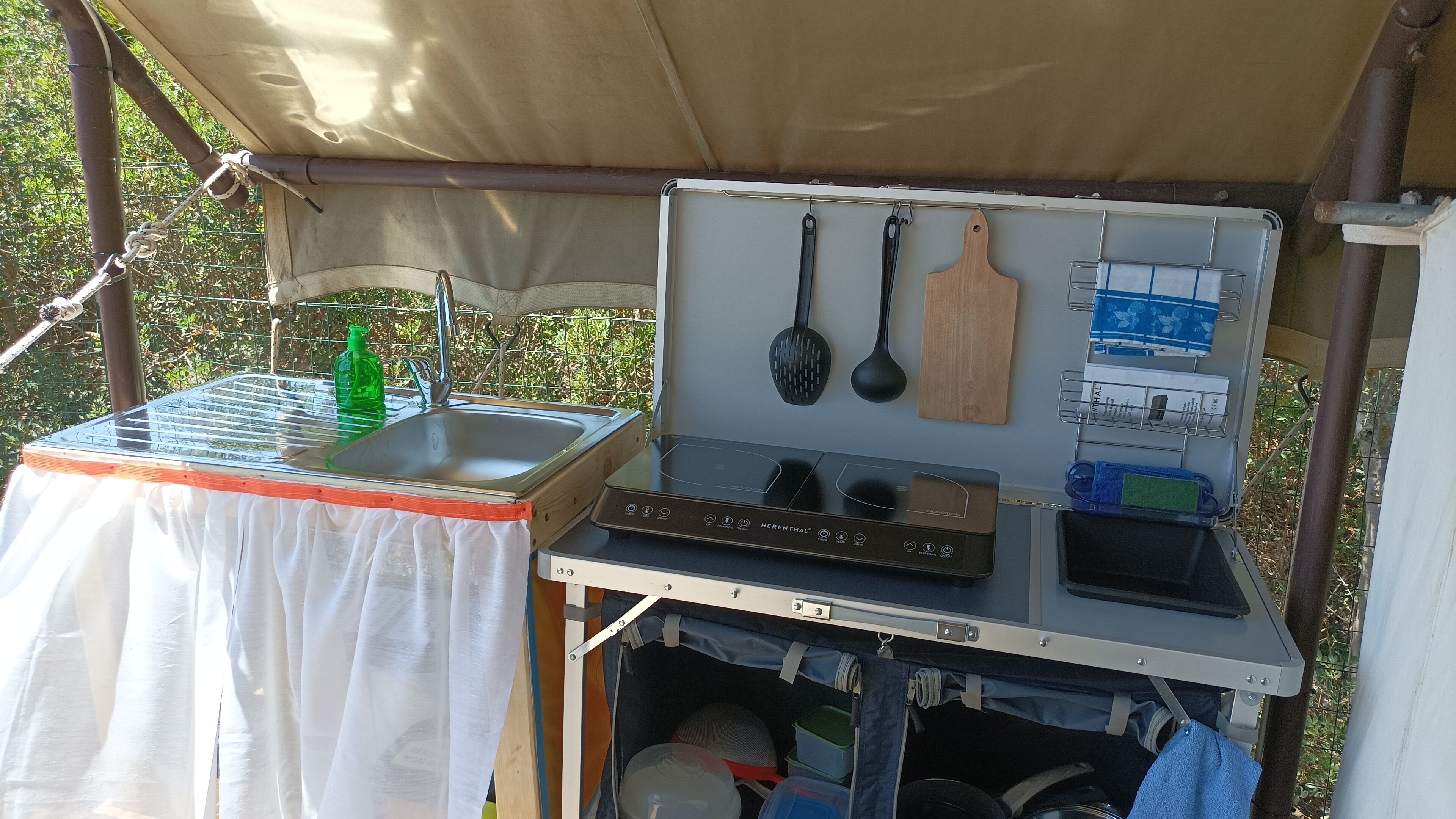 Un ensemble compact pour une cuisine d’extérieur, comprenant un évier, une cuisinière portable et divers ustensiles de cuisine.