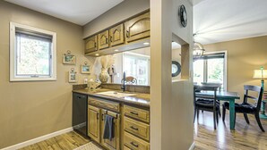 A kitchen with wooden cabinets, a sink, and a dining area with a table and chairs.