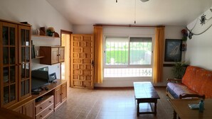 Un soggiorno con un mobile in legno, una televisione, un divano e una finestra con tende.