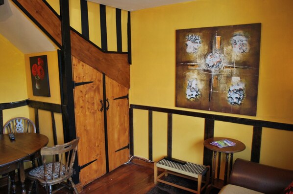Un espace repas comprenant une table et des chaises en bois, un banc et un tableau accroché au mur.