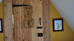 Une porte en bois ornée d’une découpe en forme d’ours, une poignée en métal noir et une petite plaque.