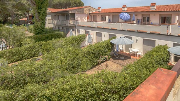 A courtyard with a pool, outdoor seating, and a view of a building with a red-tiled roof.