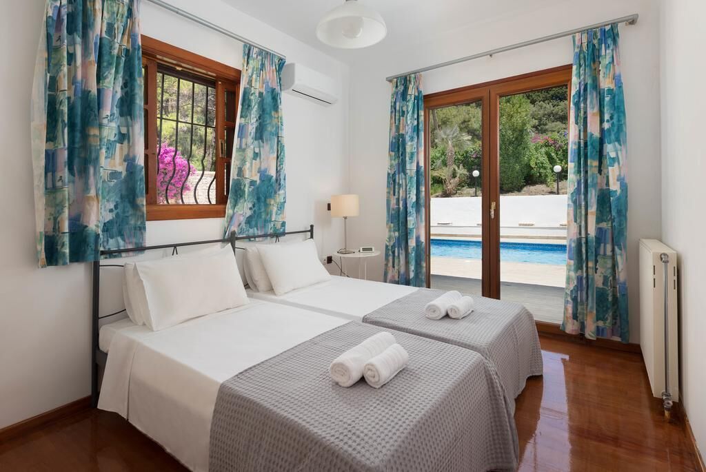 Une chambre d’hôtel avec deux lits, une vue sur la piscine et une fenêtre avec des rideaux.