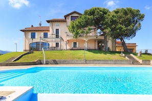 A large house with a swimming pool in front.