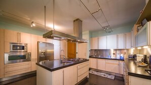 Une cuisine moderne dotée d’appareils électroménagers en acier inoxydable, de meubles en bois et d’un îlot central.