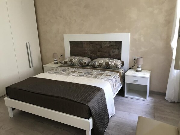 A bedroom with a bed, bedside tables, a wardrobe, and a nightstand.