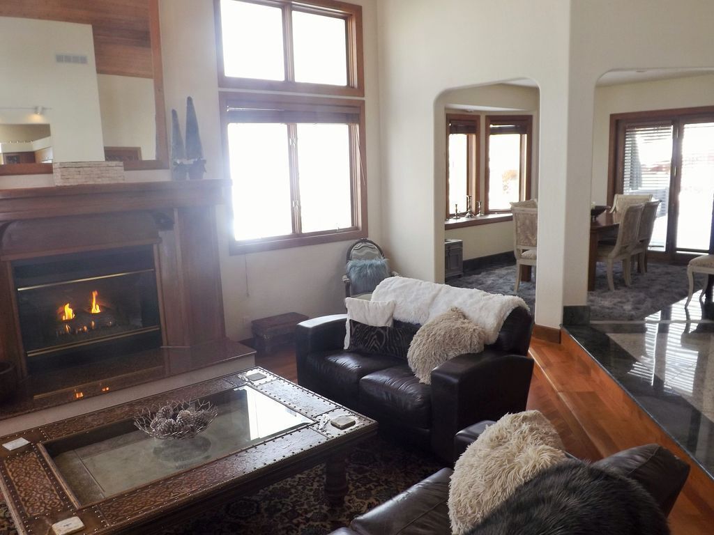 A living room with a fireplace, leather sofa, and a glass coffee table.