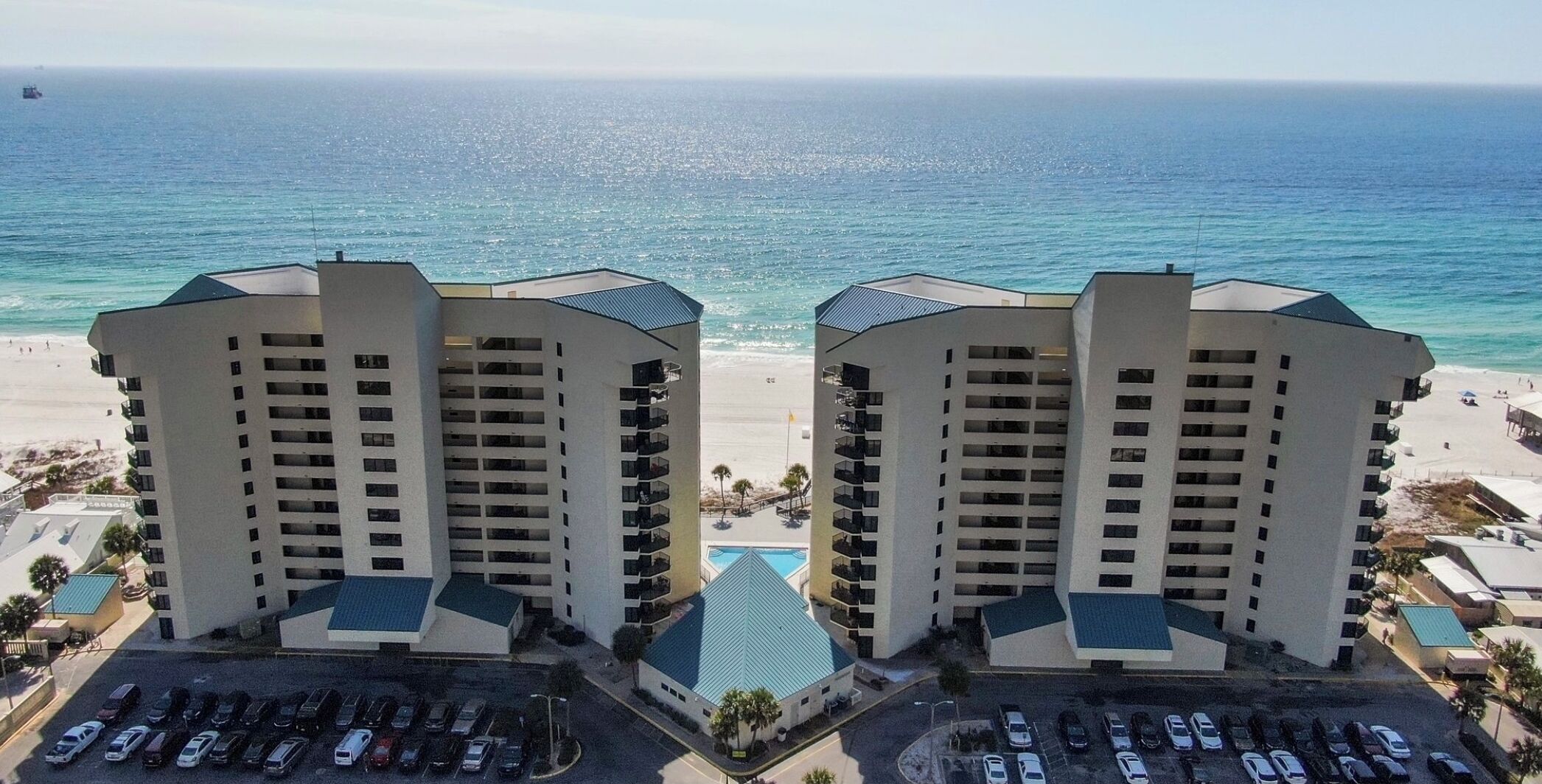 Ein Hotel am Strand mit zwei Hochhäusern, einem Parkplatz und Blick auf den Ozean.