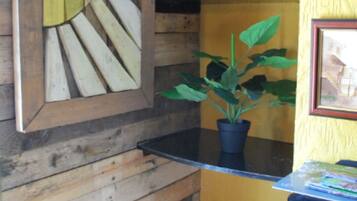 A room with a wooden wall, a black shelf with a potted plant, and a framed picture.