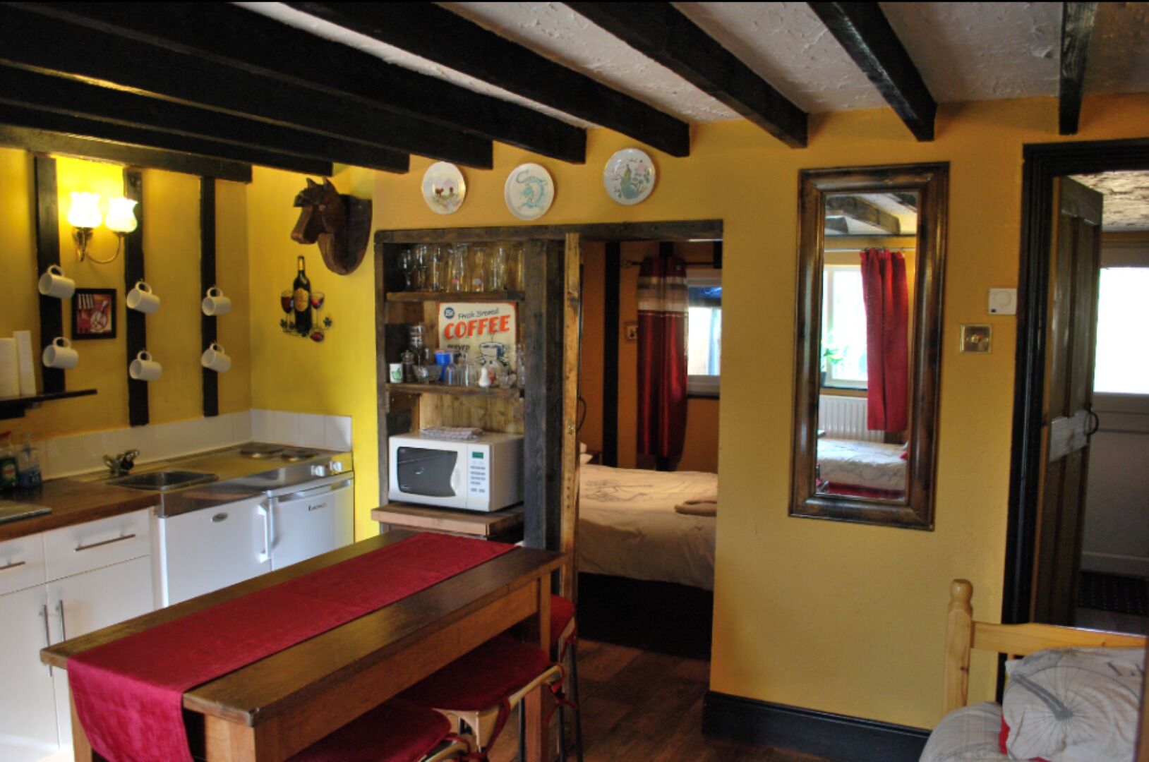 A compact kitchen with a microwave, coffee machine, and a wooden table.