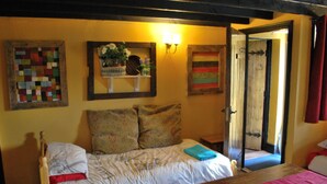 Une chambre à coucher comprenant un lit, une table de chevet, une tête de lit en bois, une étagère murale décorée de fleurs et une porte.