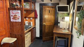 A compact kitchen with wooden cabinets, a small countertop, and a wooden door.