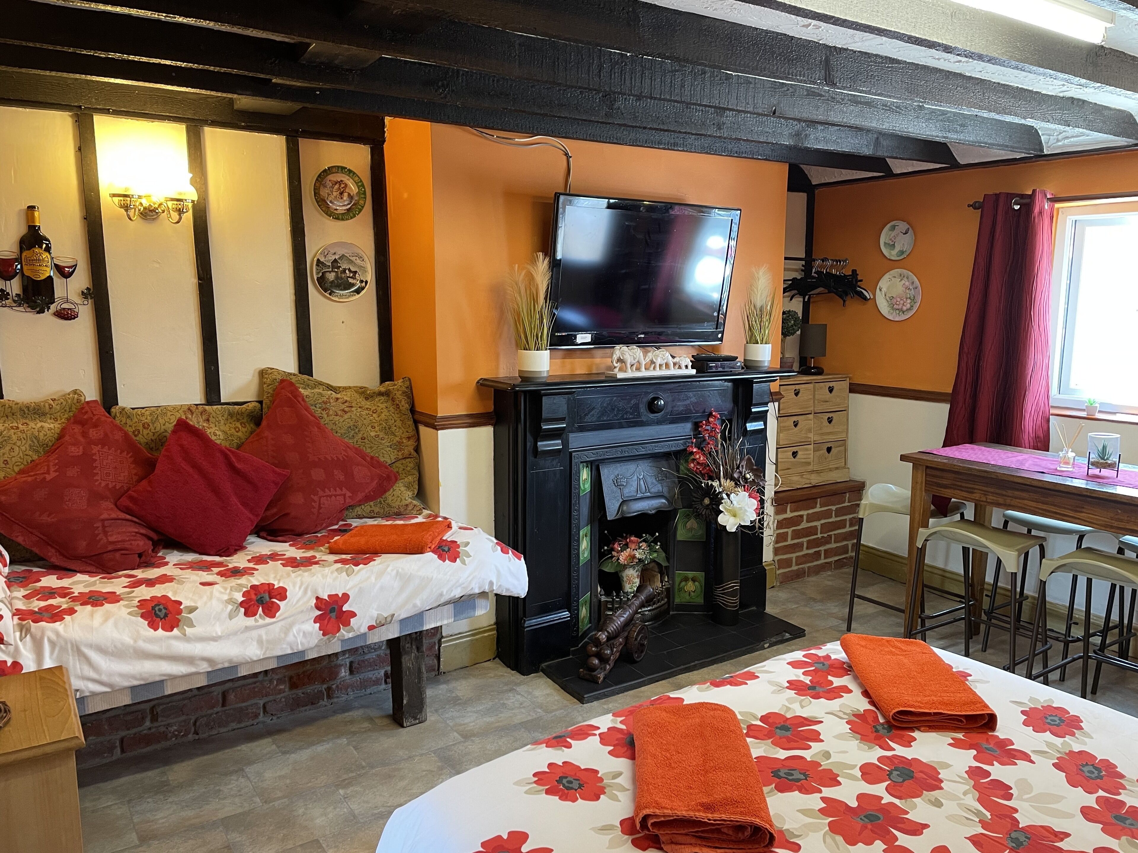 A cozy room with a bed, a fireplace, a TV, and a dining area.