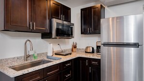 A kitchen with dark wooden cabinets, stainless steel appliances, a granite countertop, and a built-in microwave. - Apartment #3 GREAT LOCATION Zion National Park entrance as close as you can get! (Springdale)