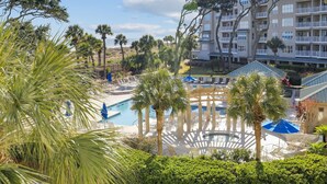 Un resort con piscina, palme e un edificio a più piani con balconi.