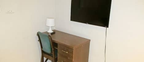 A small room with a desk, chair, and a wall-mounted TV.