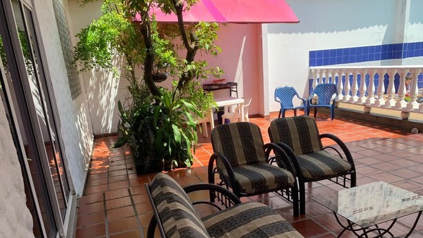 Un patio con dos sillas acolchadas, una mesita y una planta en maceta.