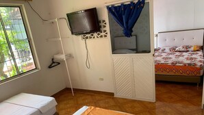 Una habitación con dos camas, televisión y ventana con vistas a la vegetación.