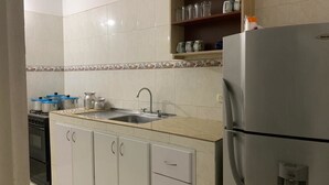 Una cocina con lavamanos, estufa, alacenas y refrigerador.