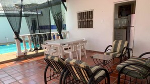 Un patio con mesa y sillas, una piscina y una zona de cocina.