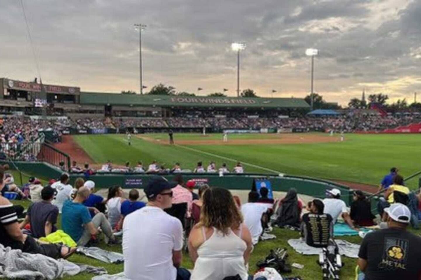 A baseball stadium with a green field, seating areas, and a crowd of spectators.
