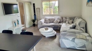 A modern living room with a sofa, a dining table, and a flat-screen TV. - Villa in St-Raphaël with private spa, enclosed garden and terrace - 5 min from the beach (Saint-Raphaël)