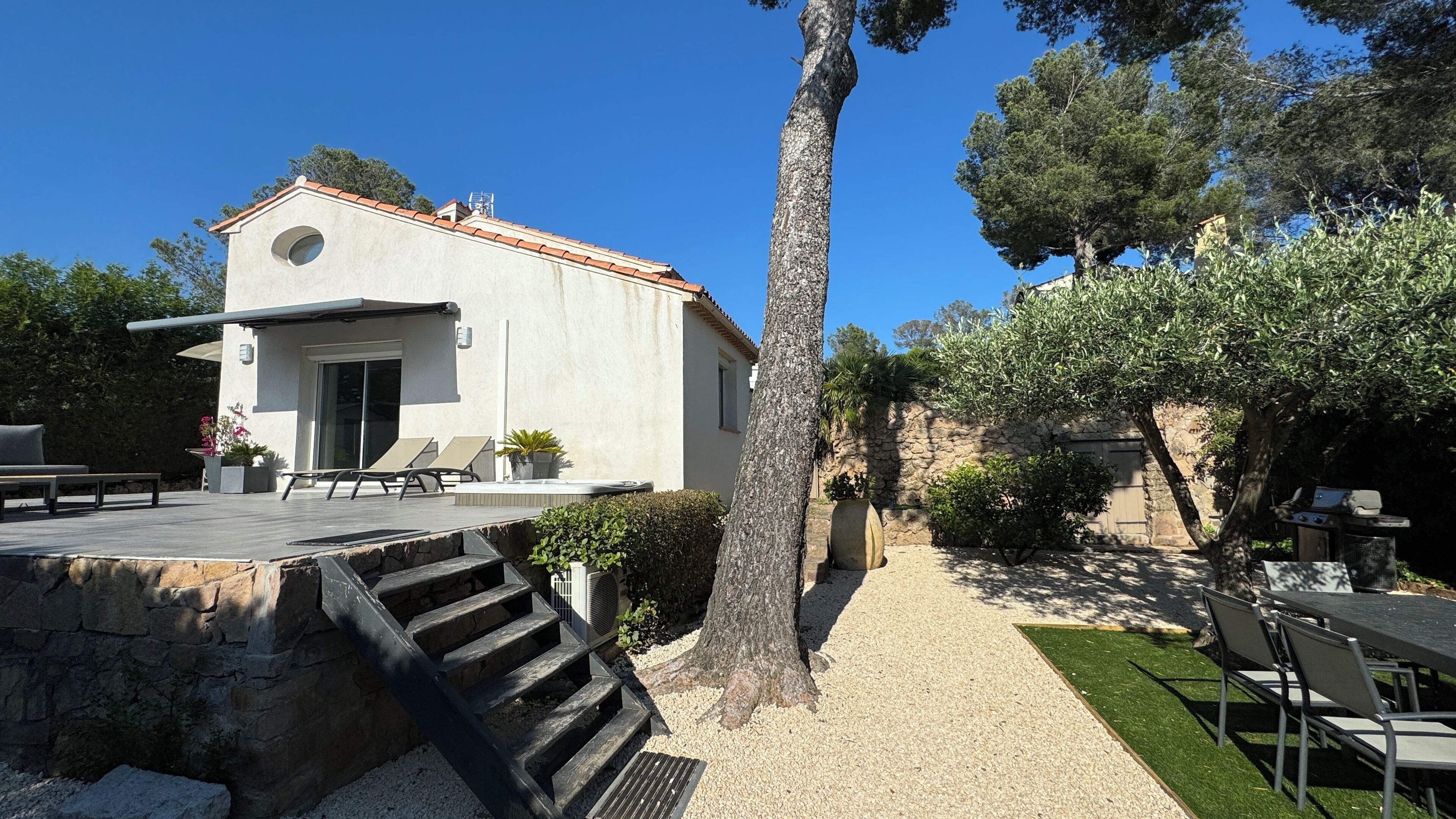 A modern house with a patio, outdoor seating, and a stone staircase leading to a door.