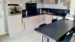 A modern kitchen with built-in appliances, a central island, and a dining area. - Villa in St-Raphaël with private spa, enclosed garden and terrace - 5 min from the beach (Saint-Raphaël)