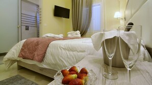 Ein Hotelzimmer mit einem Bett, einem Nachttisch mit einem Glas Wasser und einer Schale Erdbeeren.