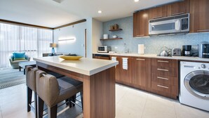 A modern kitchen with wooden cabinets, a built-in microwave, and a washing machine. - Large 2 BR 2 BA Apartment at The Carillon Wellness Resort (Miami Beach)