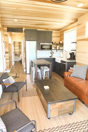 A compact living space with a kitchenette, a dining area, and a seating area with a sofa and chairs.