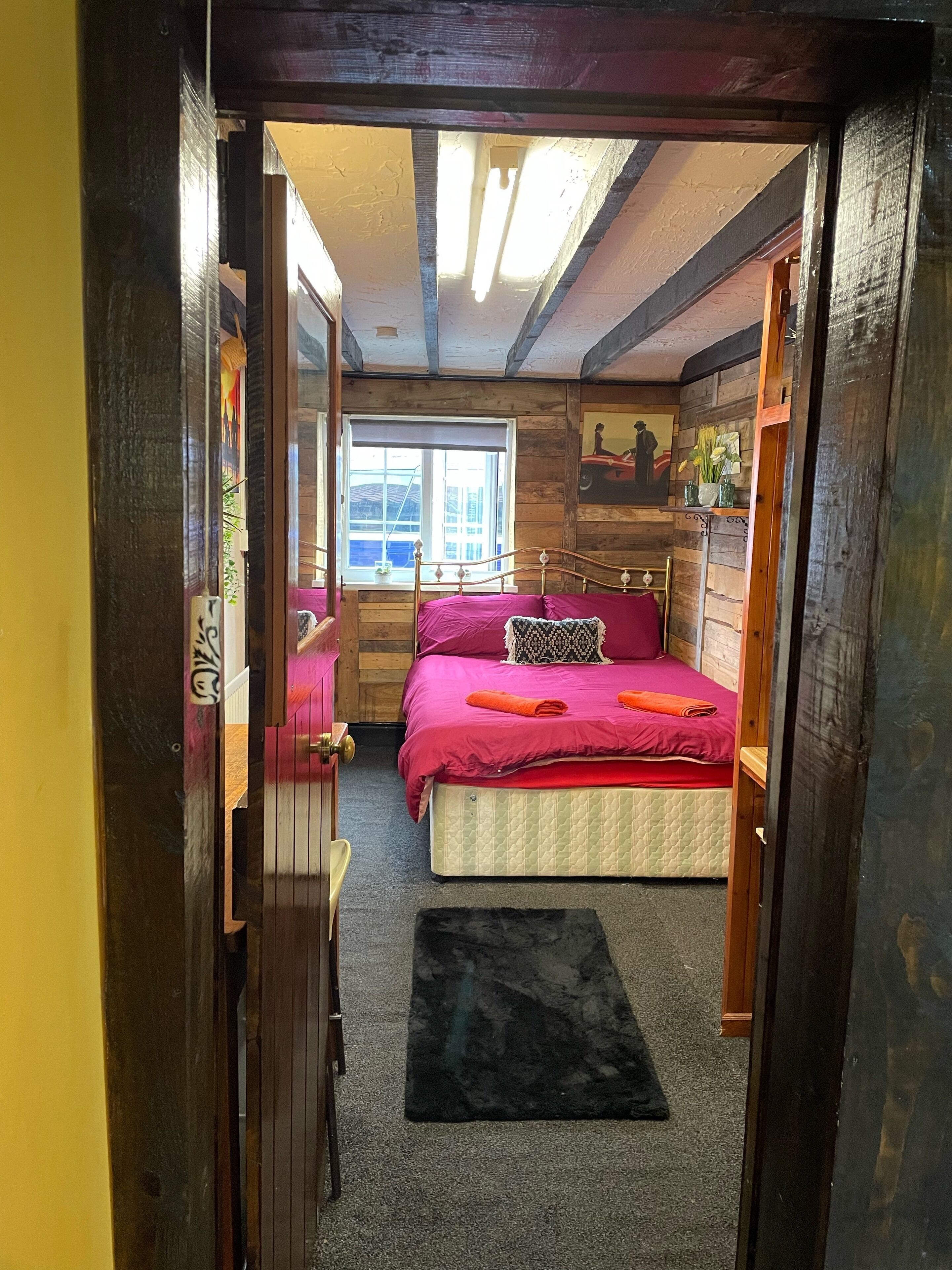 A compact bedroom with a bed, a window, and a door.
