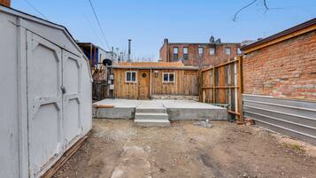 Urban oasis with a compact backyard featuring a wooden structure and brick wall.