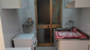 Eine kleine Küche mit Kühlschrank, Spüle und Arbeitsfläche.