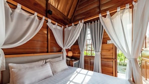 A wooden cabin bedroom with a bed, curtains, and a window. - Honba Lagi Beach Resort (La Gi)