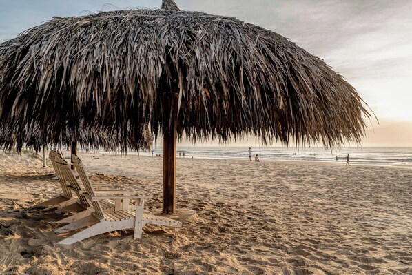 Aan een privéstrand, wit zand, ligstoelen, parasols