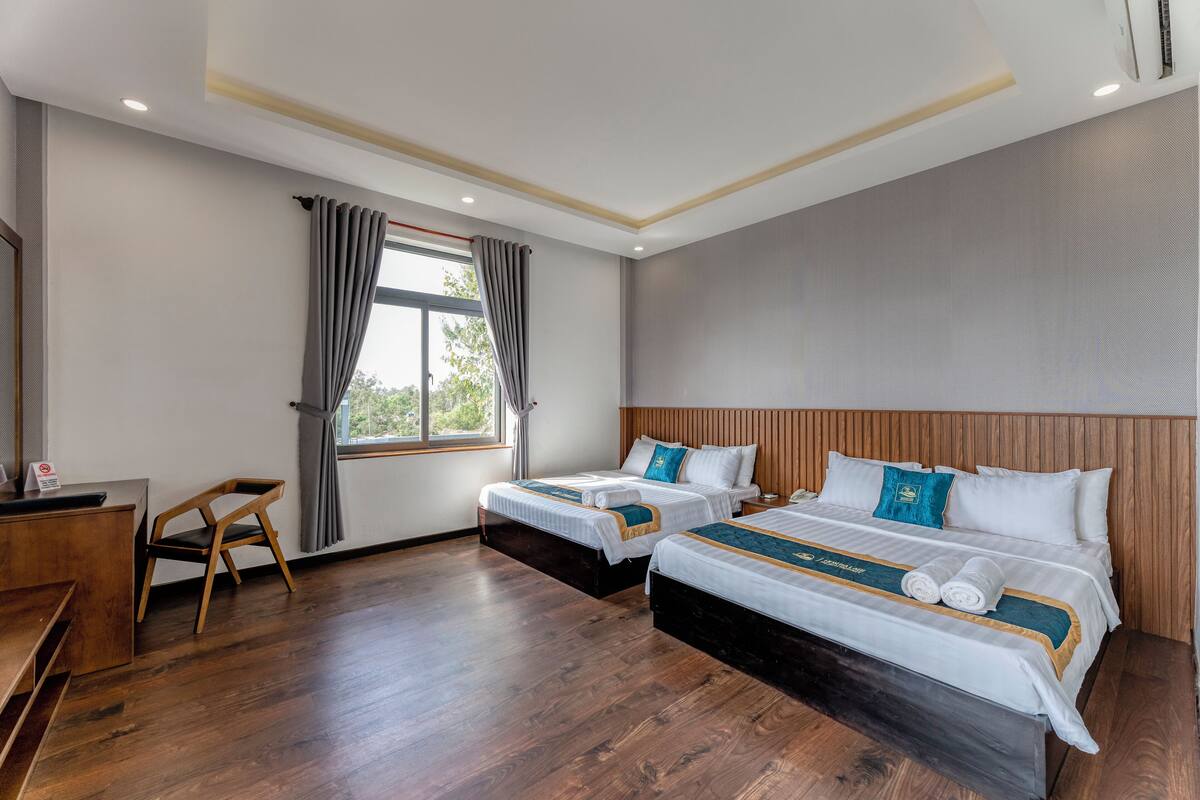 Habitación de hotel con dos camas, un escritorio y una silla.