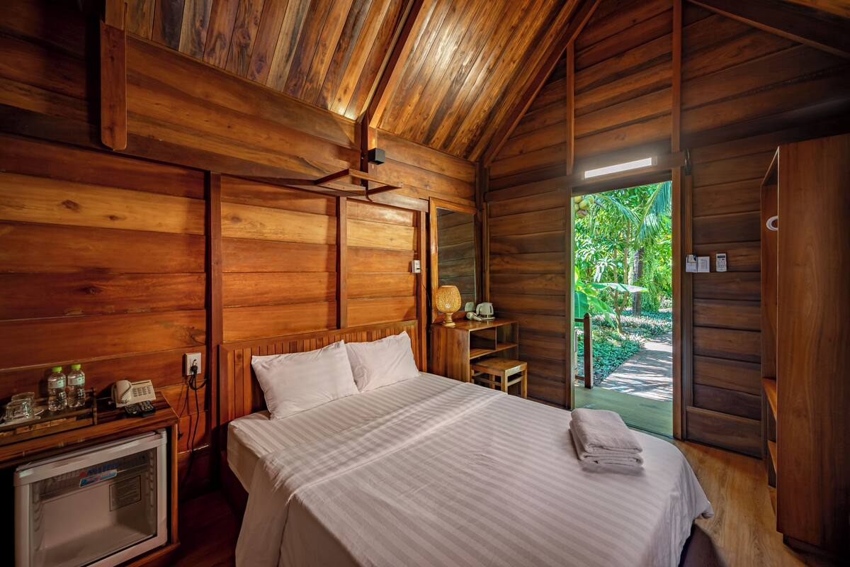 Una habitación de cabaña de madera con una cama, un escritorio, una silla y un televisor pequeño.
