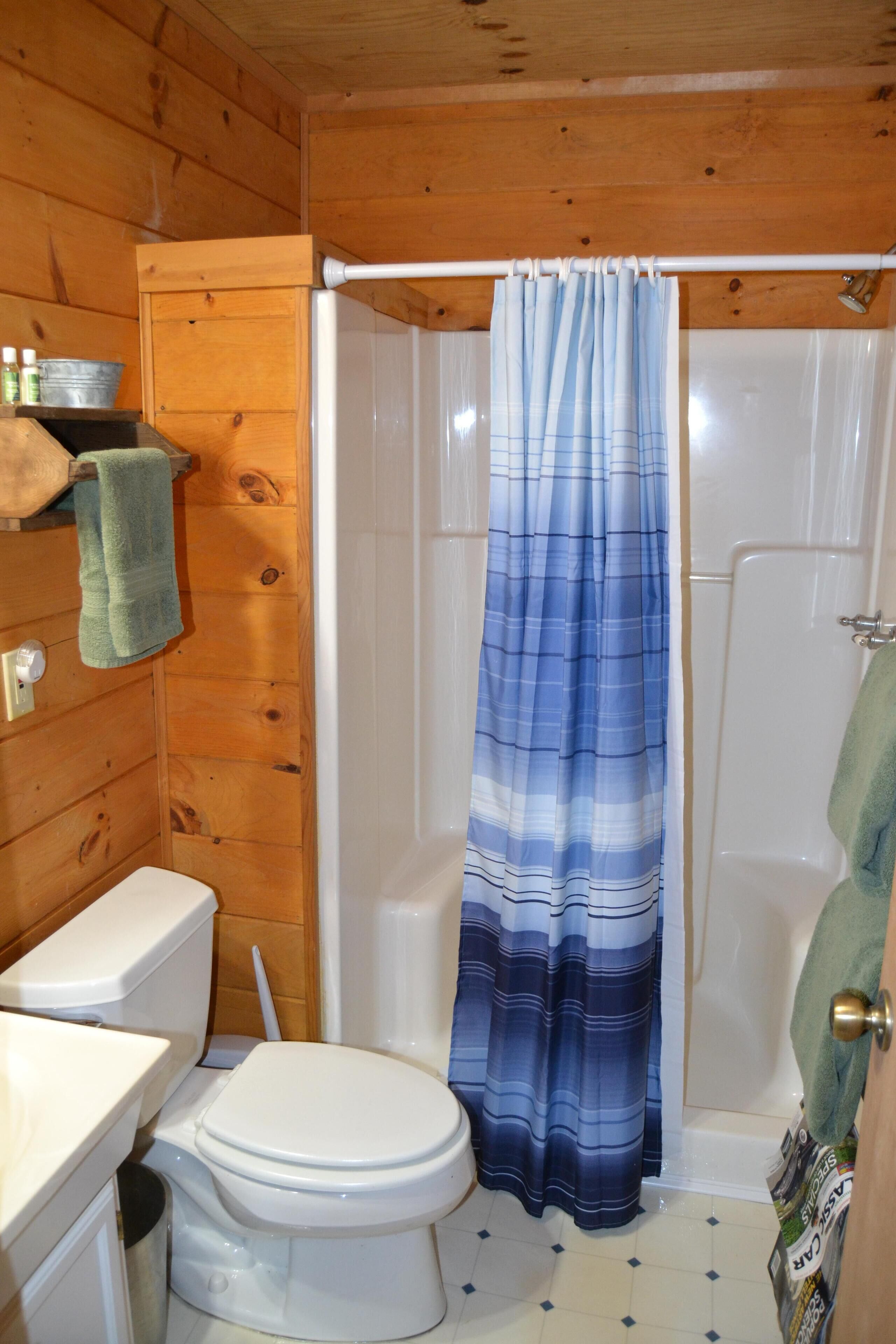 Ein Badezimmer einer Holzhütte mit Toilette, Badewanne und Duschvorhang.