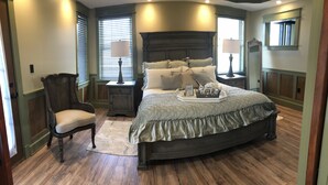 A bedroom with a large bed, two bedside tables, a chair, and a dresser. - Guest quarters at the inn - 205 (North Beach)