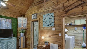 A wooden cabin interior with a television, cabinets, a decorative wall piece, and a washing machine. - 4WD / AWD Adventure For 2 - Private Setting Near Great Smoky Mtns National Park (Sevierville)