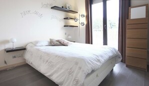 Un dormitorio con cama, mesitas de noche, estanterías y un armario.