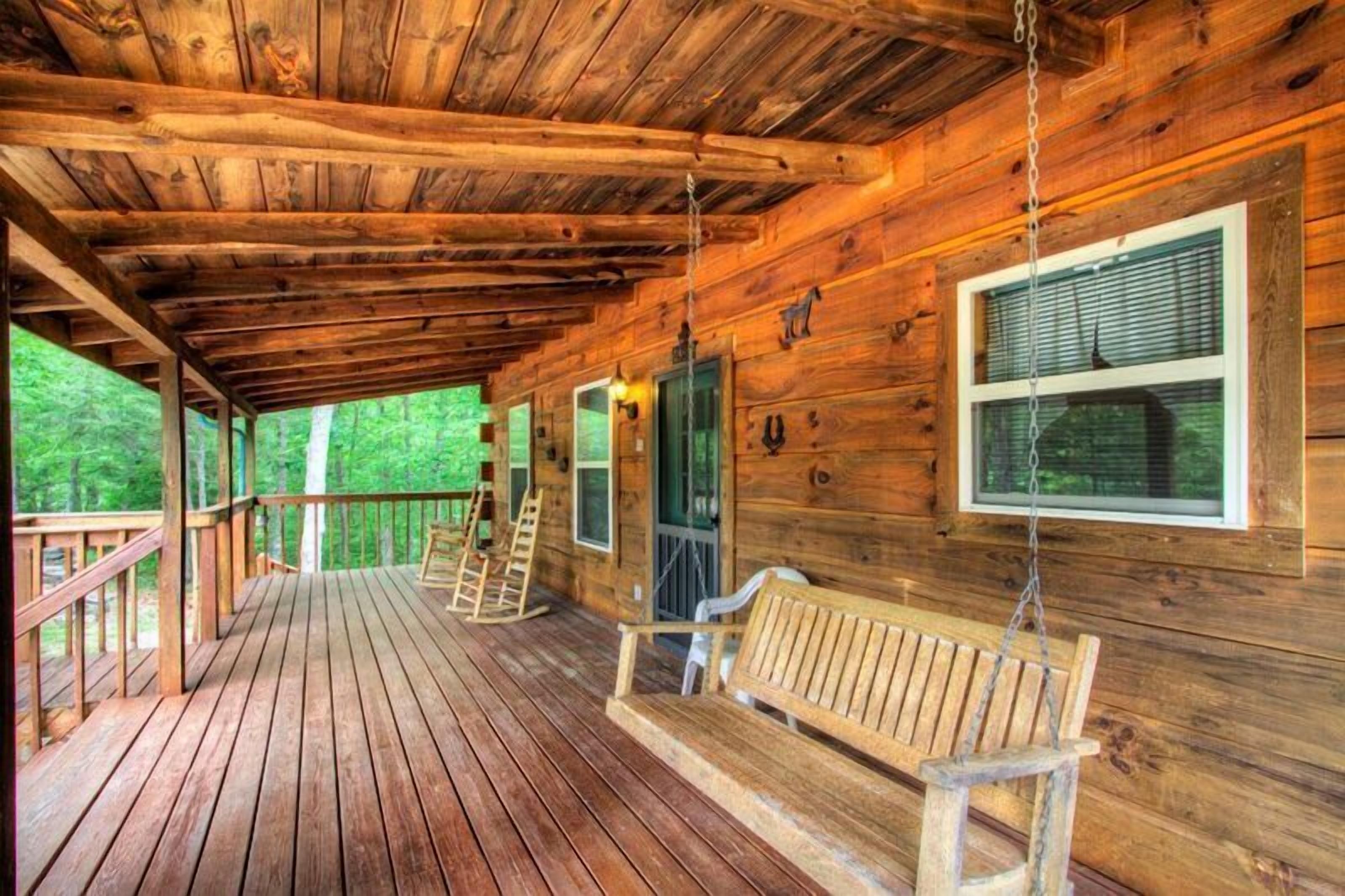 A wooden cabin with a porch, rocking chairs, and a ladder.