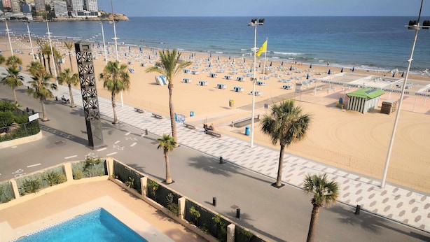 Ein Strand mit Liegestühlen und Sonnenschirmen, ein Schwimmbad und Blick aufs Meer.