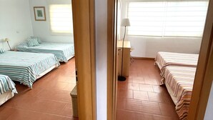 A room with two beds, a floor lamp, and a window with blinds.