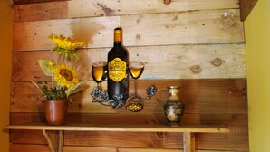 A wooden shelf with a bottle, two glasses, and a vase.