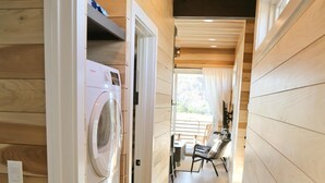 Un área de lavandería con lavadora y secadora, paredes de madera y una zona de comedor con sillas y una mesa.